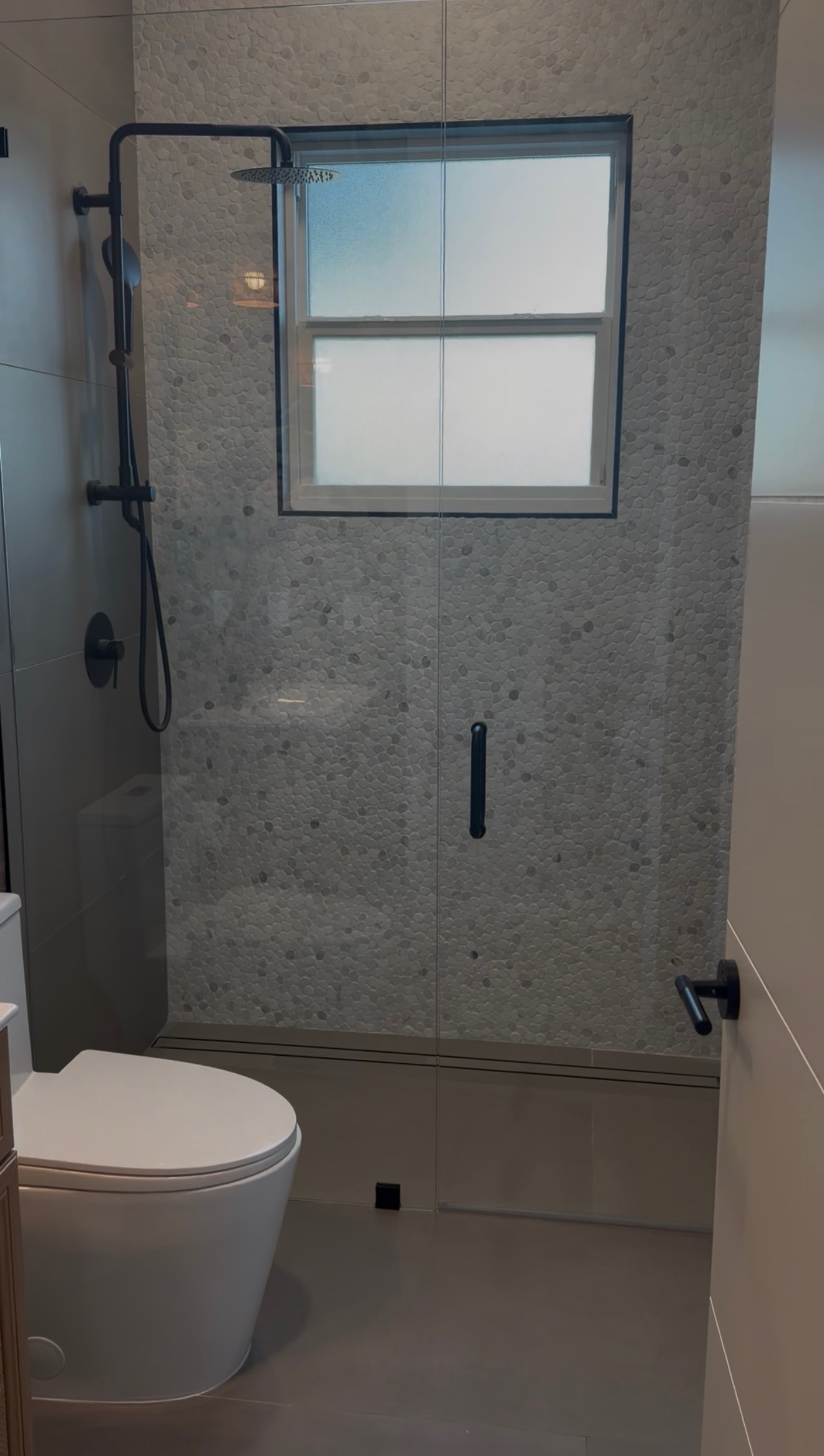 Pebble Tile Shower with Glass Enclosure project by Worldwide Floors Corp in Miami-Dade or Broward
